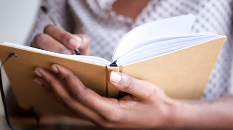Woman writing in plain journal image