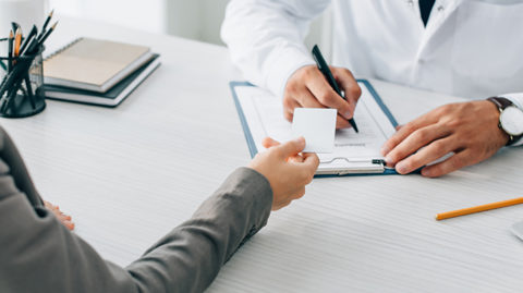 Woman handing over card to doctor