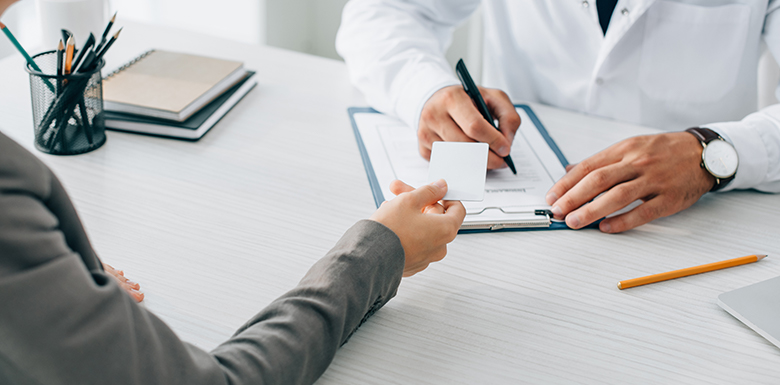 Woman handing over card to doctor