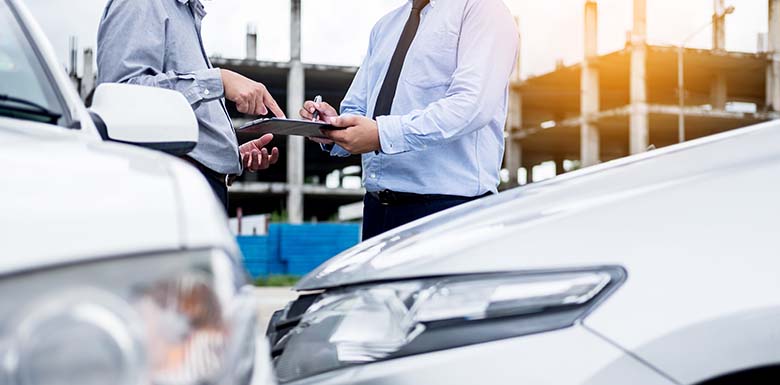 Two men talking over car accident with clipboard