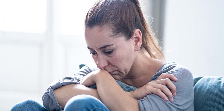 Adult woman with arms crossed looking sad on sofa